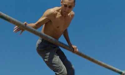 a shirtless man riding a skateboard on a rail