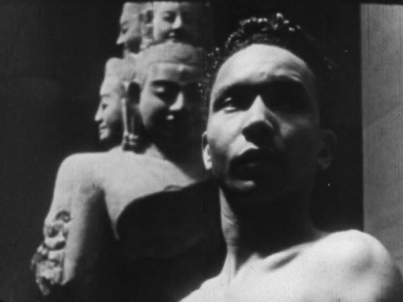 a black and white photo of a man standing in front of statues