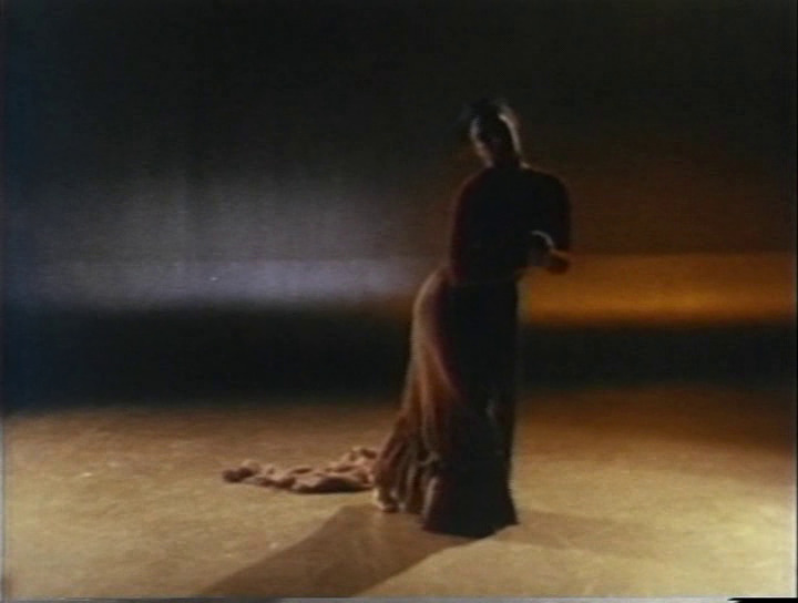 a woman in a long dress standing in a dark room