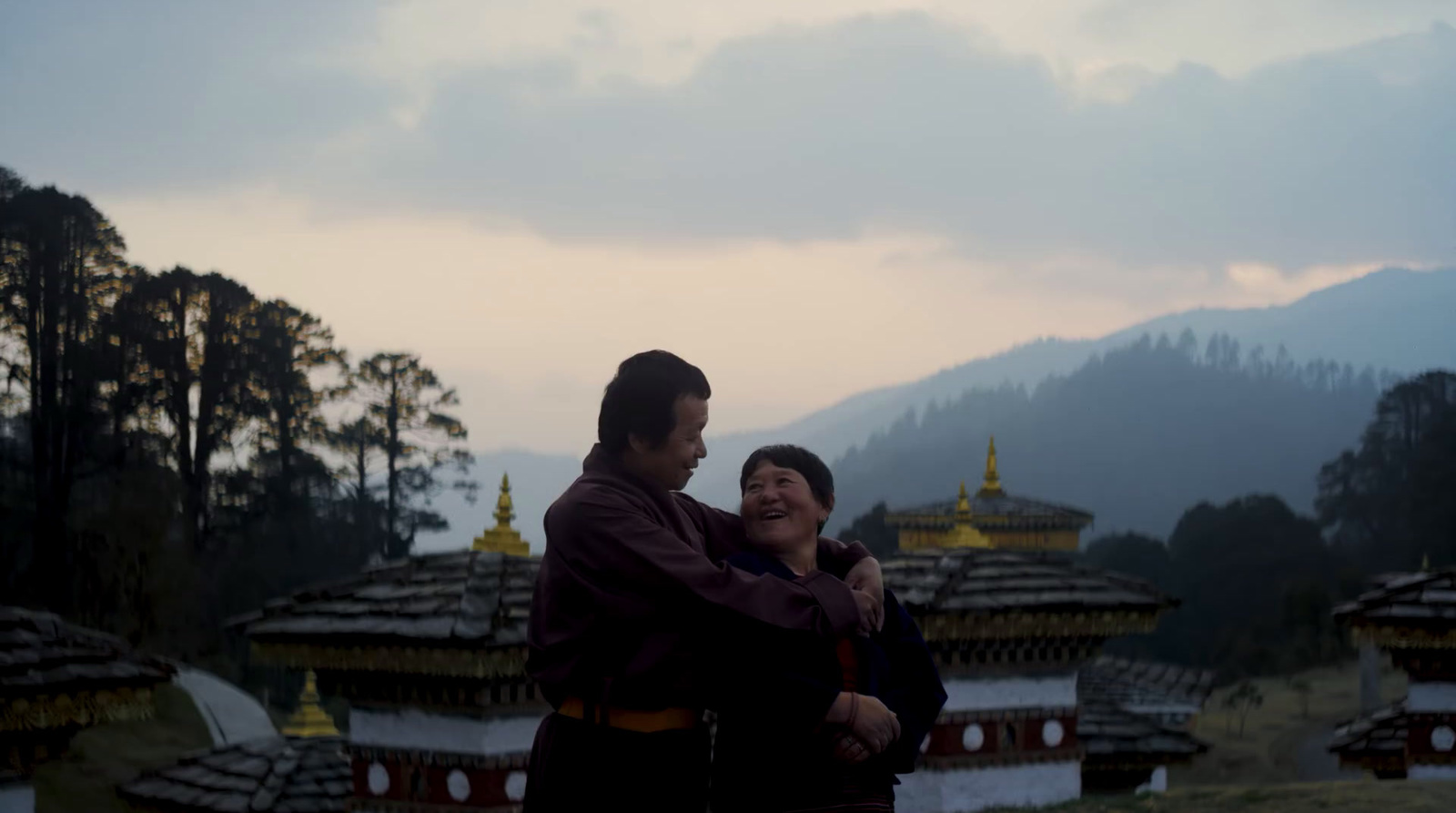 a man and a woman standing in front of a mountain