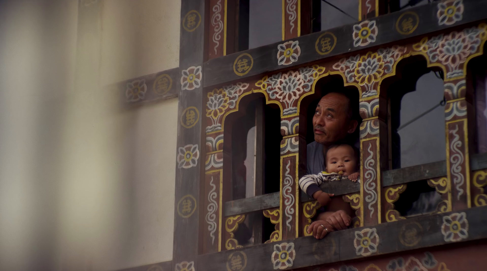 a man holding a baby looking out of a window