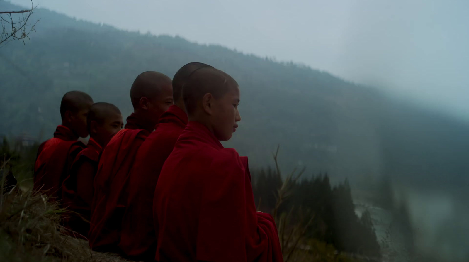 a group of men in red robes sitting on a hill