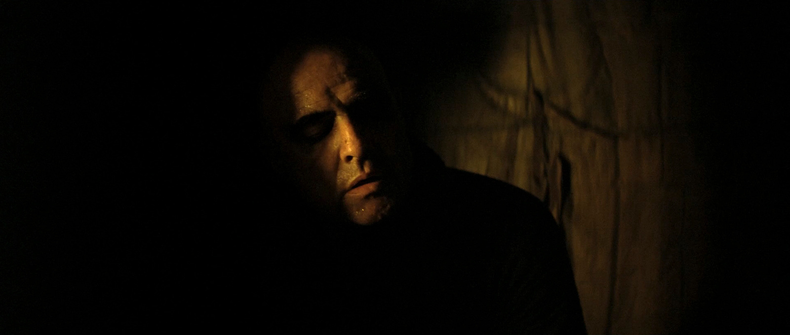 a man in a dark room with his eyes closed