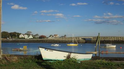 a white boat sitting on top of a river next to a bridge