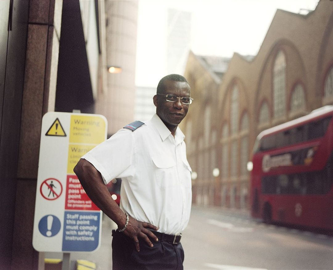 a man standing on the side of a street next to a red bus