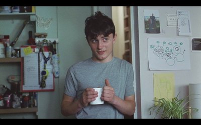 a young man holding a coffee cup in a kitchen