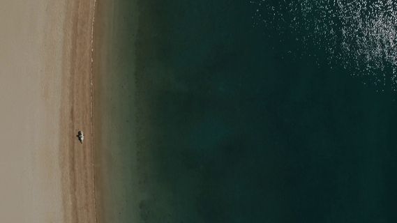 an aerial view of a beach with a boat in the water