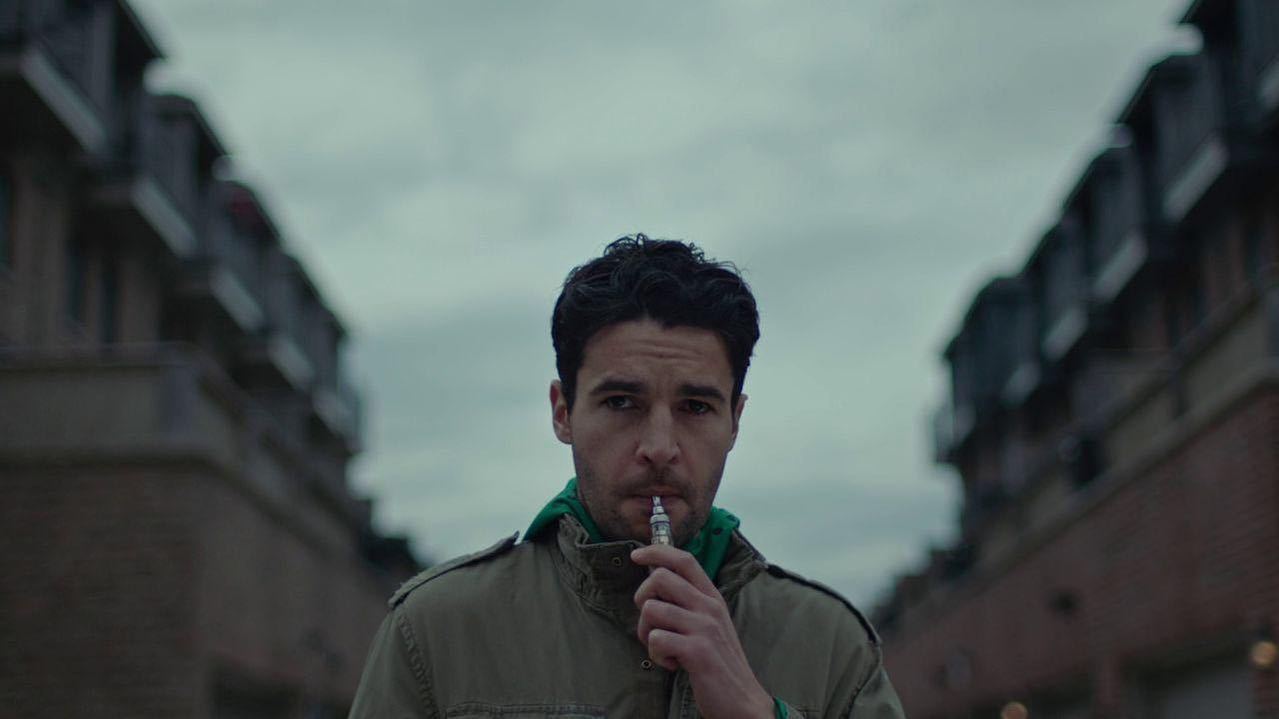 a man standing in the middle of a street with a cigarette in his mouth