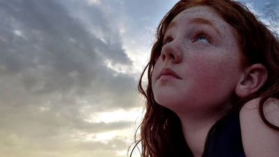 a girl looking up at a cloudy sky