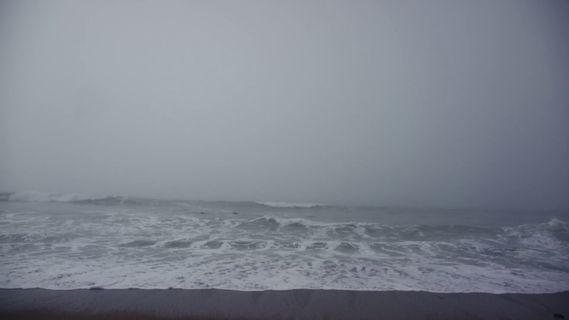 a view of the ocean from a beach in a foggy day