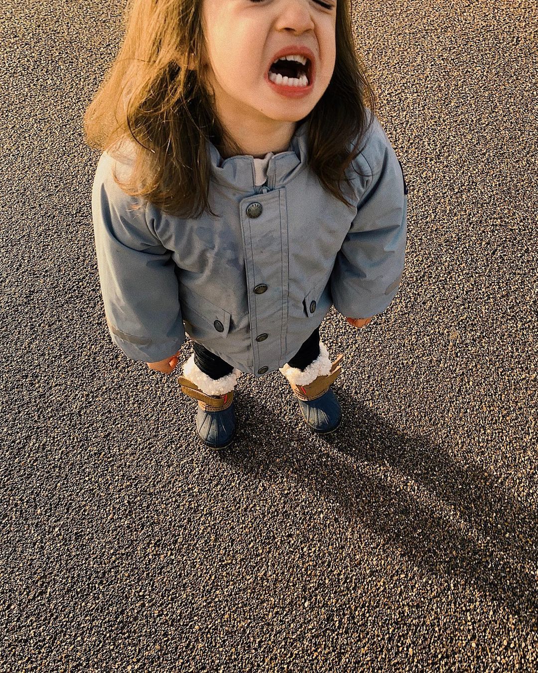 a little girl standing on top of a parking lot