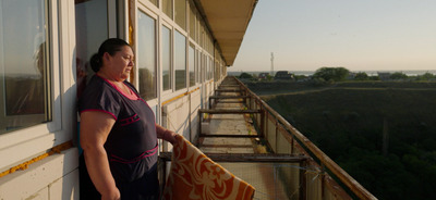 a woman standing on a balcony holding a surfboard