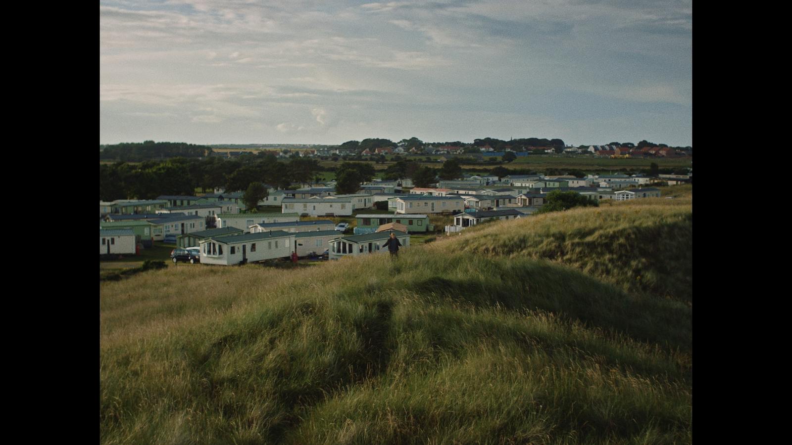 a group of trailers parked on top of a grass covered hillside