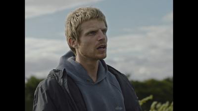 a man with blonde hair wearing a gray hoodie