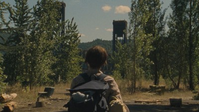 a person sitting on a bench in the woods