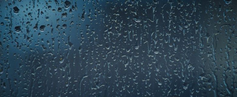 rain drops on a window with a blue sky in the background