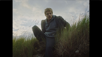 a man sitting in a field of tall grass