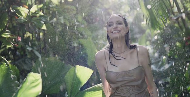 a woman standing in the rain in a forest