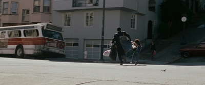 a man riding a horse down a street next to a bus