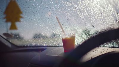 a drink sitting on the dashboard of a car