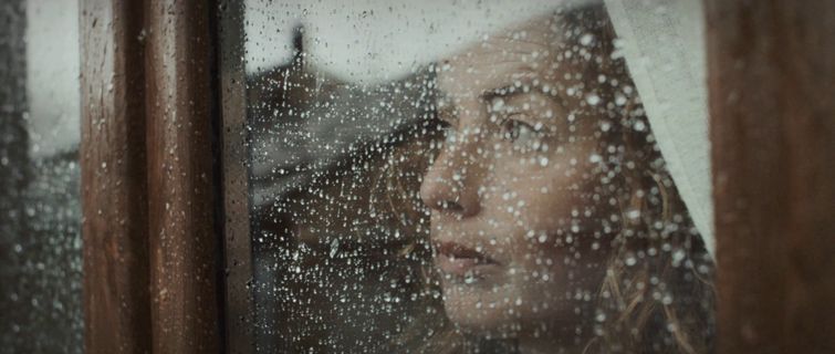 a woman looking out of a window in the rain