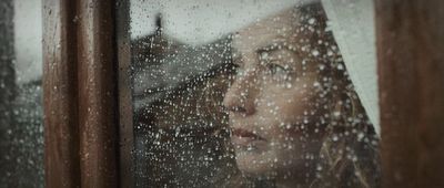 a woman looking out of a window in the rain