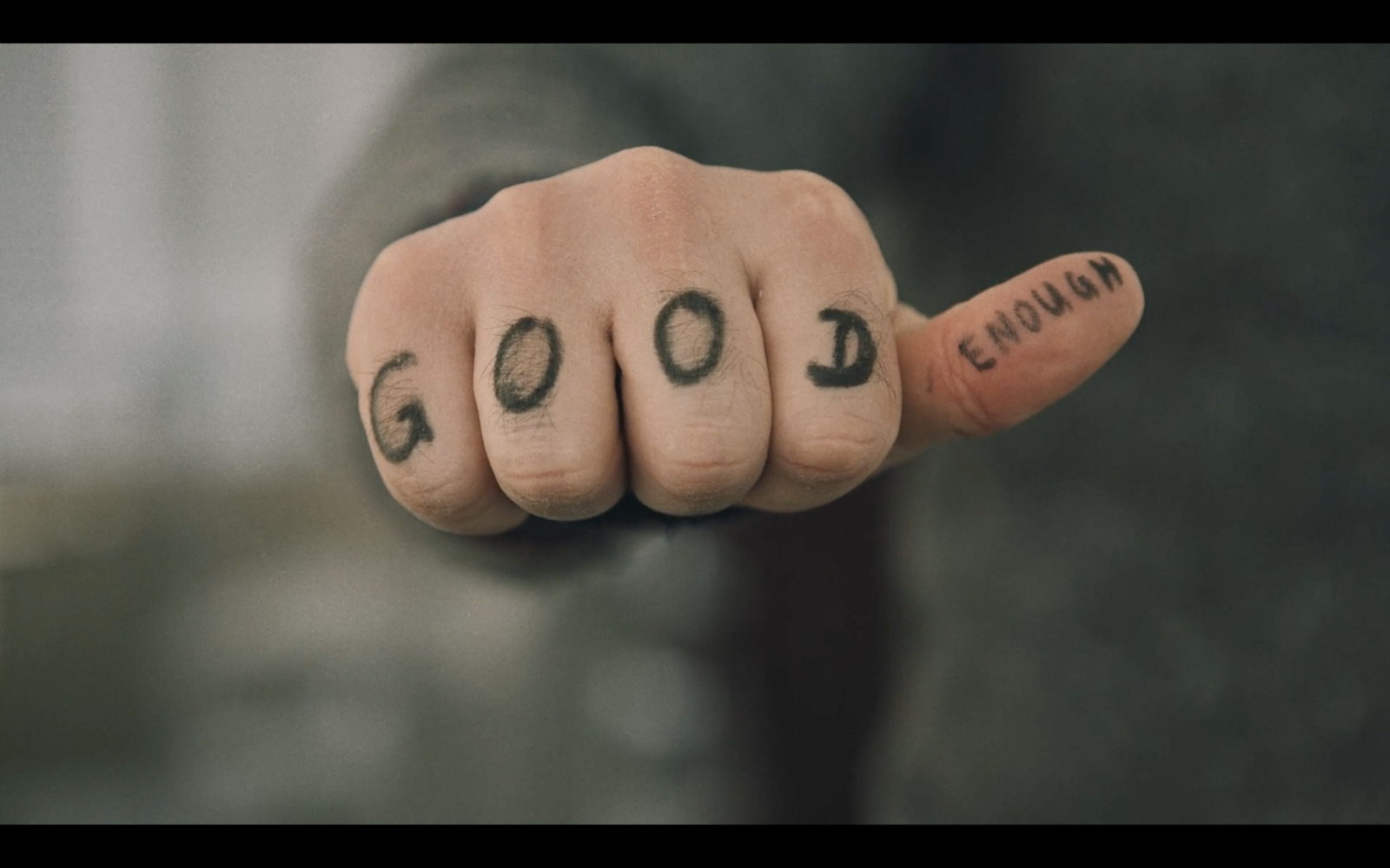 a person with a tattoo on their fingers pointing at the camera