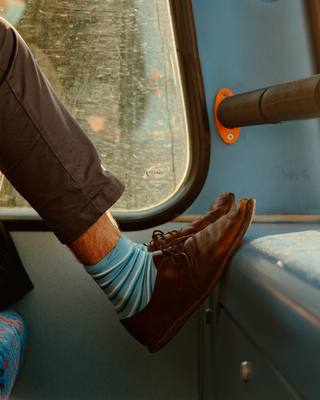 a man sitting on a bus with a pair of brown shoes