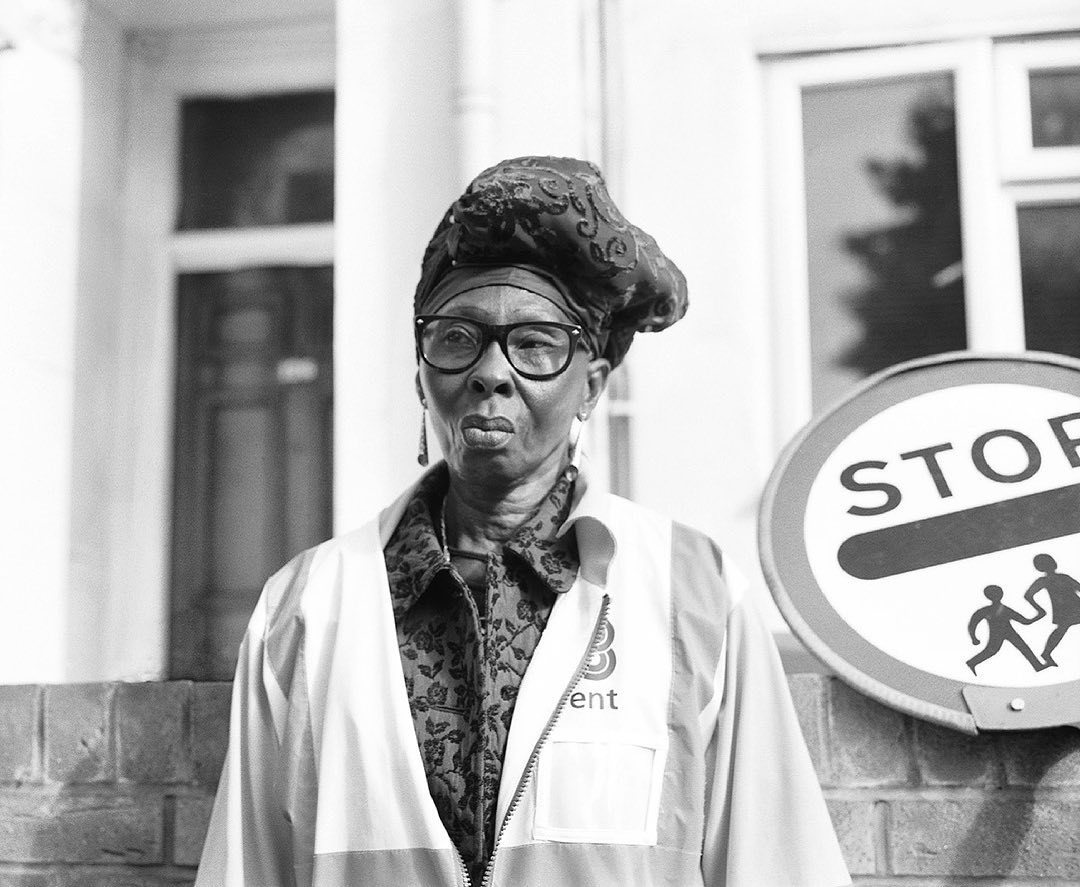 a black and white photo of a man in front of a stop sign