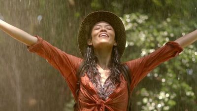 a woman in a red dress and hat standing in the rain