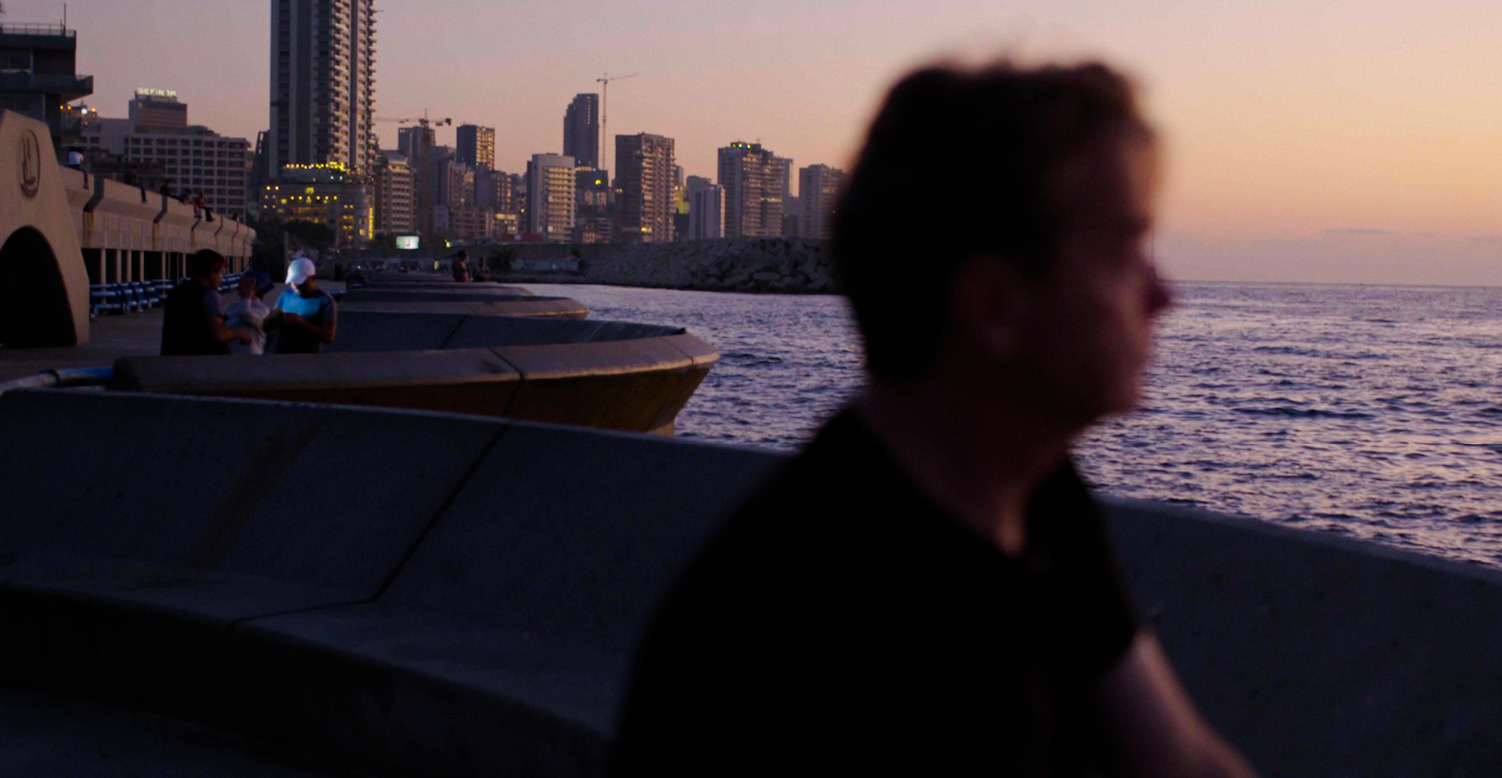 a man sitting on a bench near the ocean