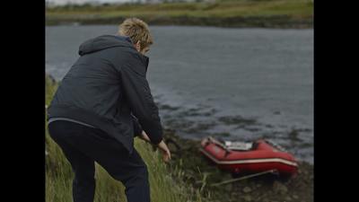 a person in a black jacket standing next to a body of water