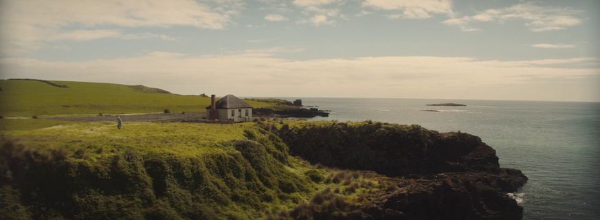 a house sitting on top of a cliff next to the ocean