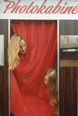 two women standing in front of a red curtain