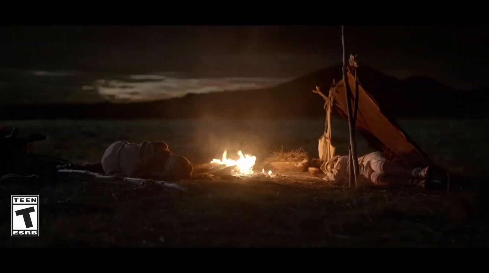 a person laying on the ground next to a campfire