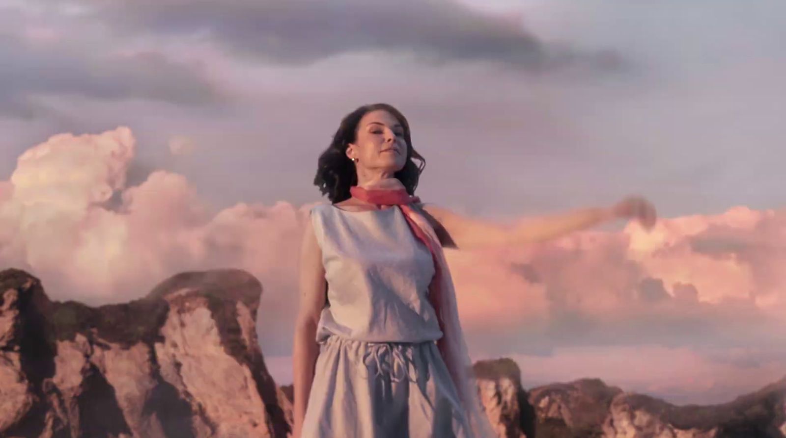 a woman in a dress standing in front of a mountain