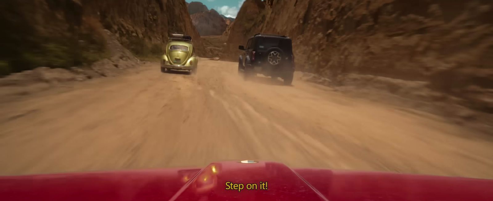 a car driving down a dirt road next to a truck