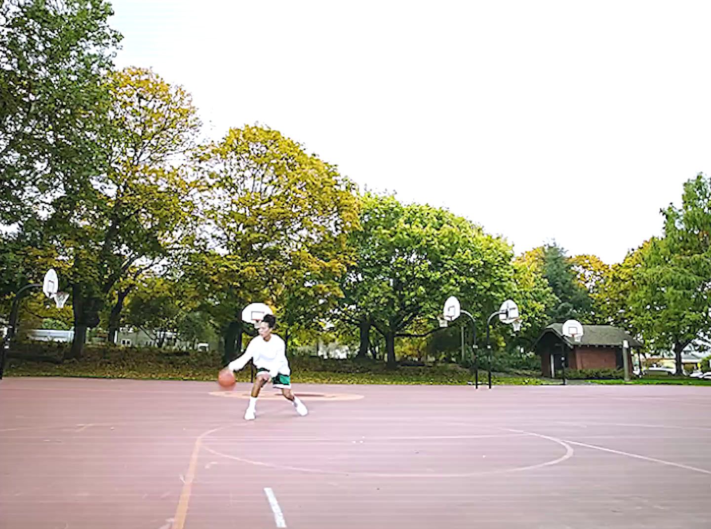 a young man holding a basketball on top of a basketball court