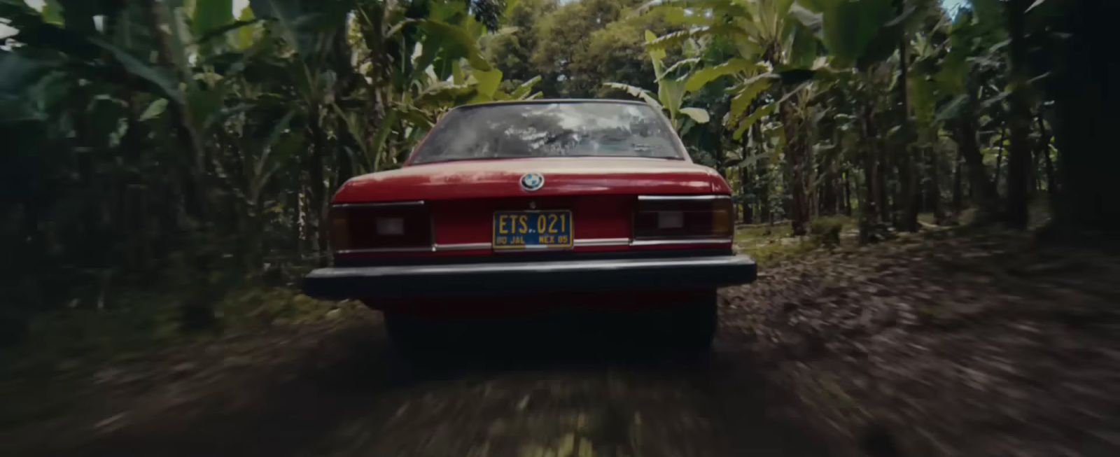 a red car driving down a dirt road