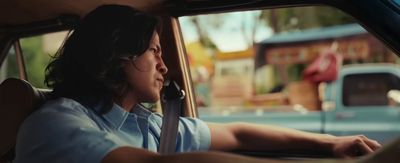 a man sitting in a car with his hand on the steering wheel