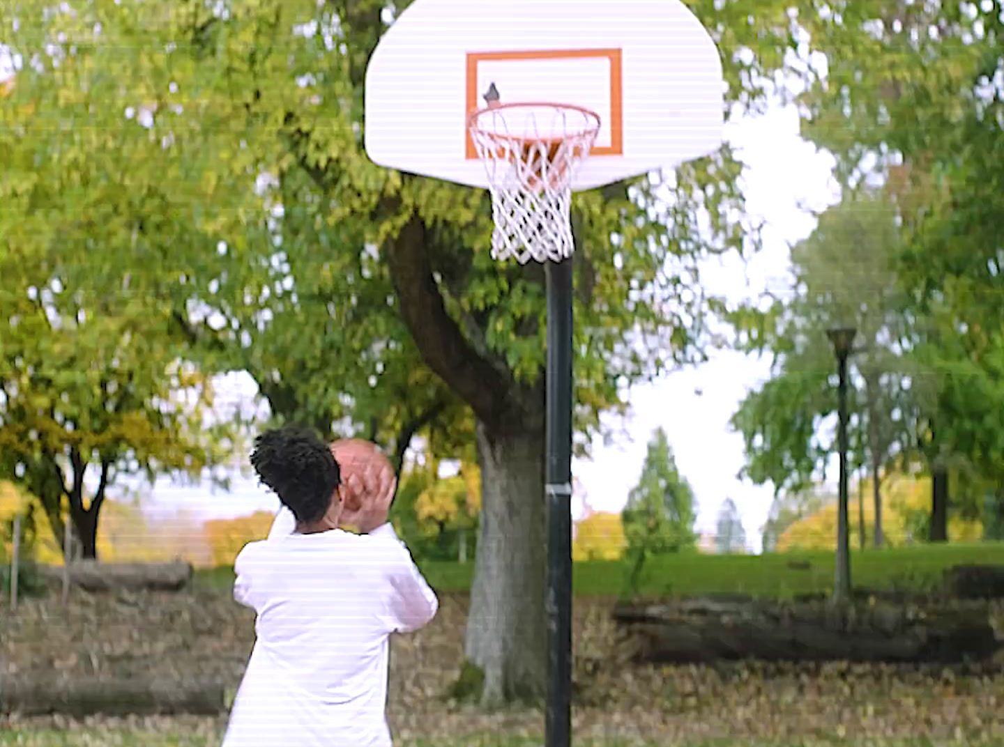 a man is playing basketball in a park