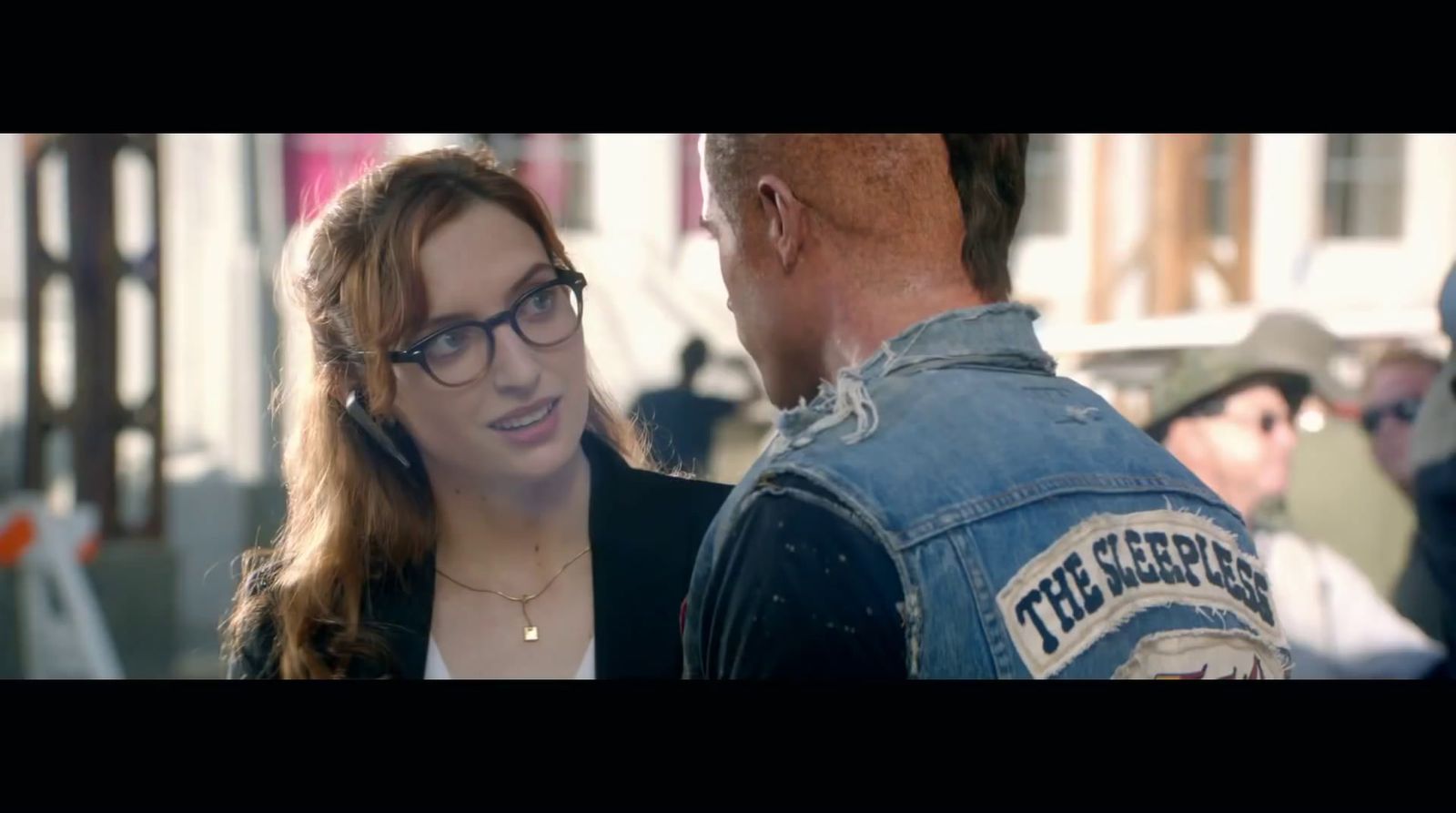 a woman talking to a man in a denim jacket