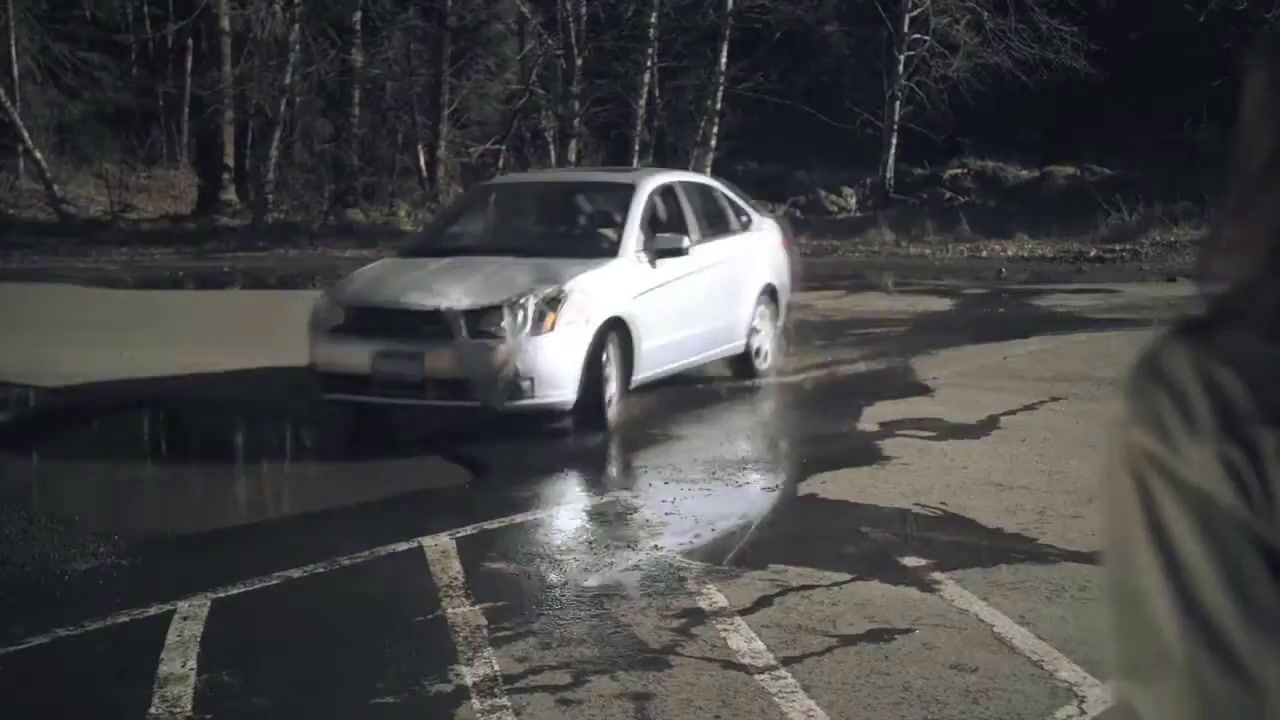 a white car driving down a wet road