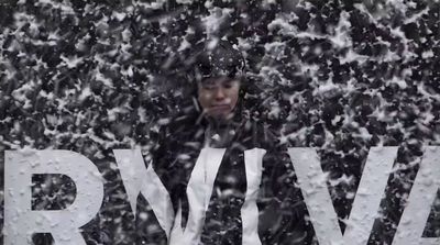 a man standing in front of a sign covered in snow