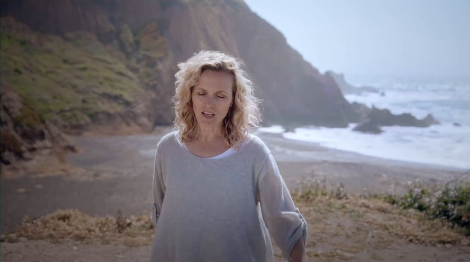 a woman standing on top of a beach next to the ocean