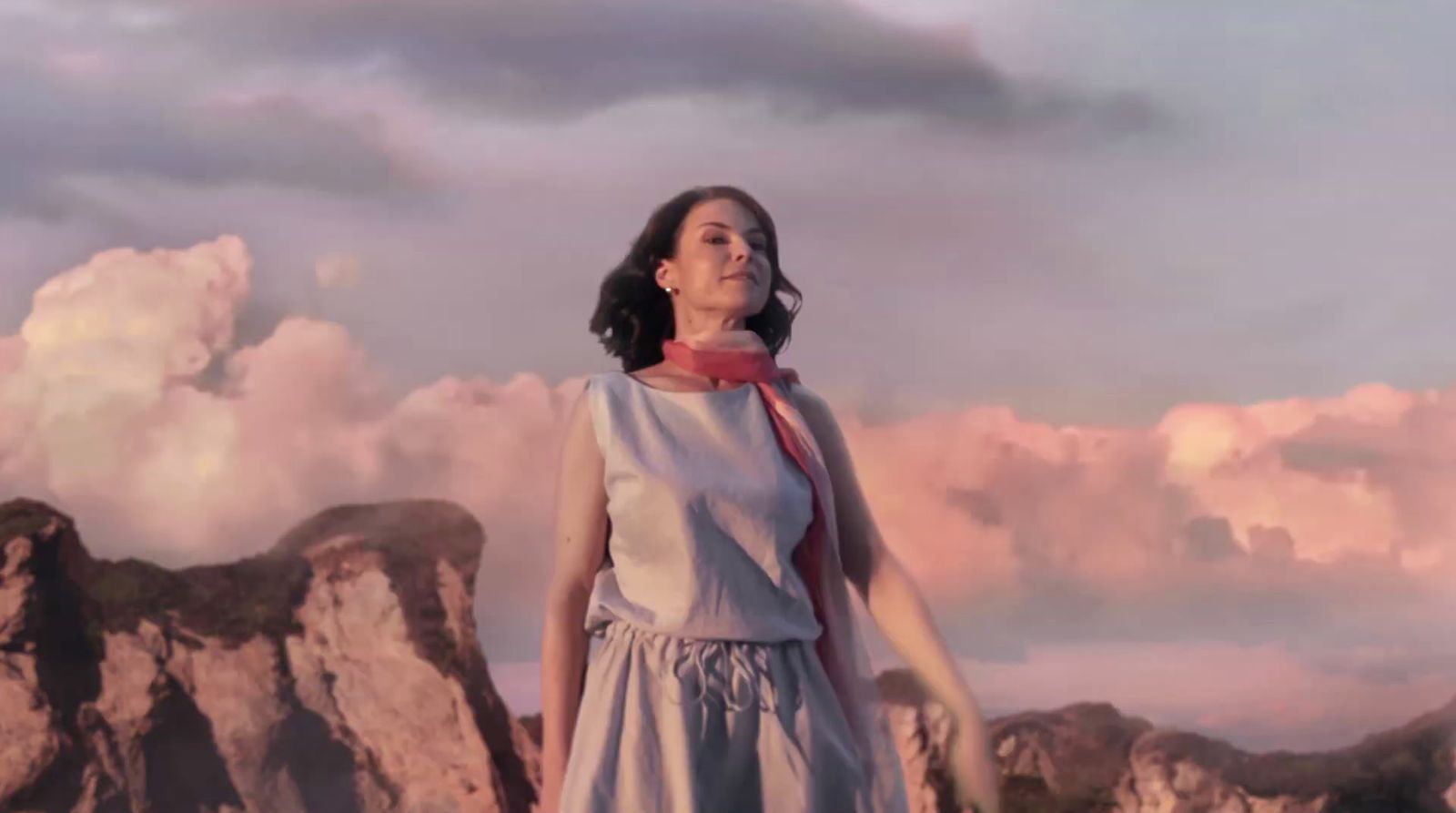 a woman in a dress standing in front of a mountain