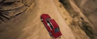 a red car driving down a dirt road