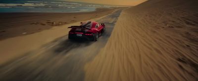 a red sports car driving down a sandy road