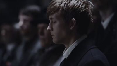 a man in a suit and tie sitting in front of a group of people