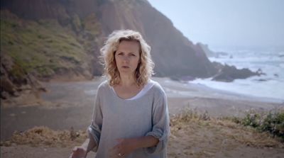 a woman standing on top of a beach next to the ocean